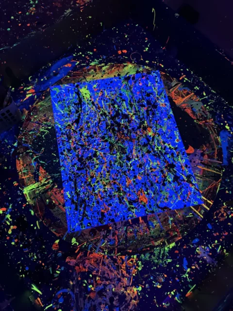 Świecące niebieskie płótno po chlapaniu farbą fluo