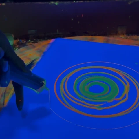 Malowanie strzykawką z farbą fluo na stole spin art