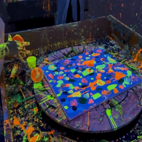 Ręce dziecka wylewające farbę fluo na wirujący stół