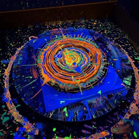Świecący obraz spin art na obrotowym stole w sali UV