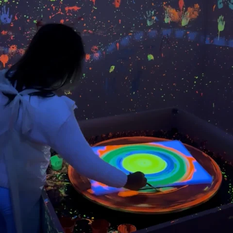 Dziewczynka maluje na obrotowym stole spin art w świetle UV w GlamLama Rzeszów